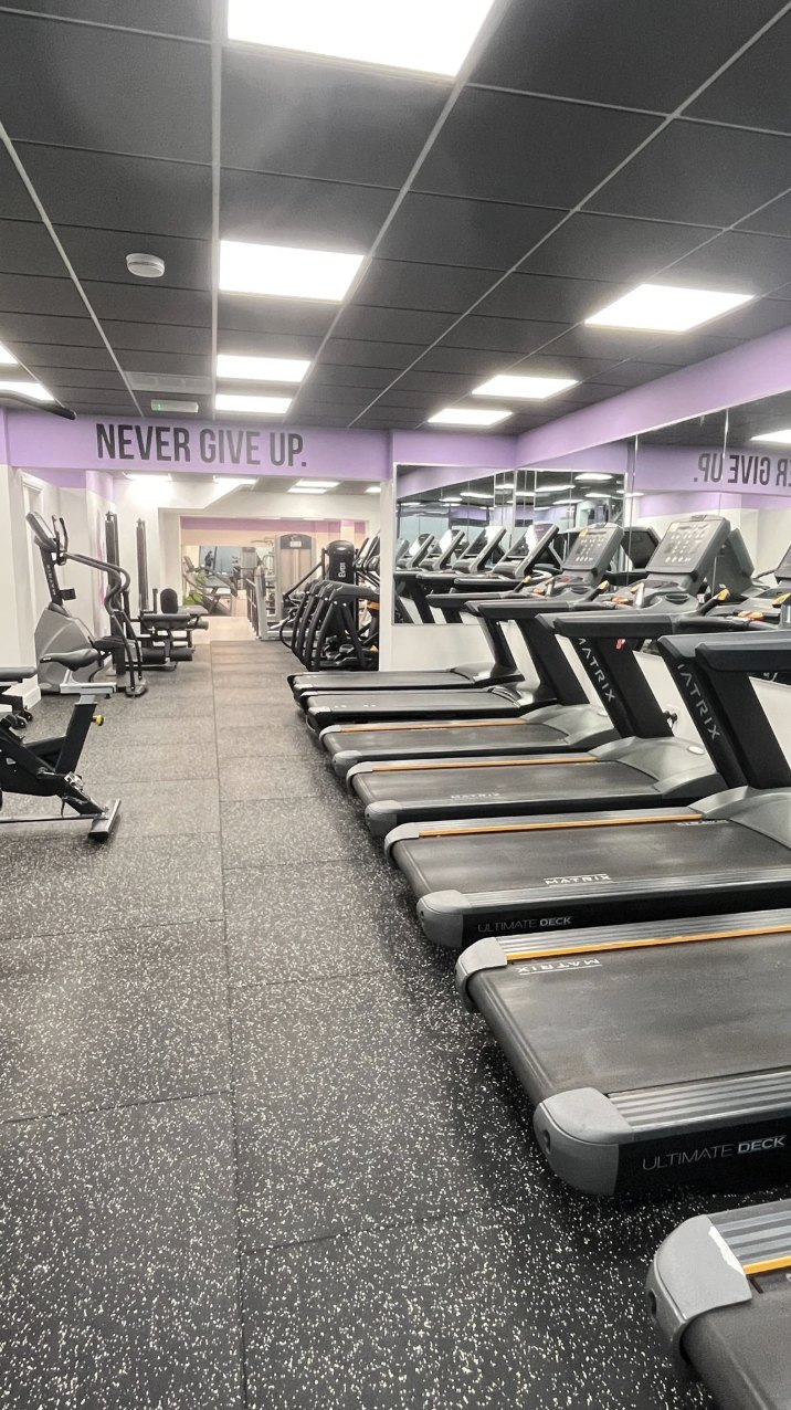 A long row of treadmills beneath the painted slogan Never Give Up